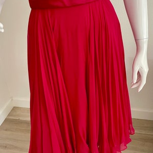 May include: A bright pink, knee-length dress with a pleated skirt and a satin waistband.
