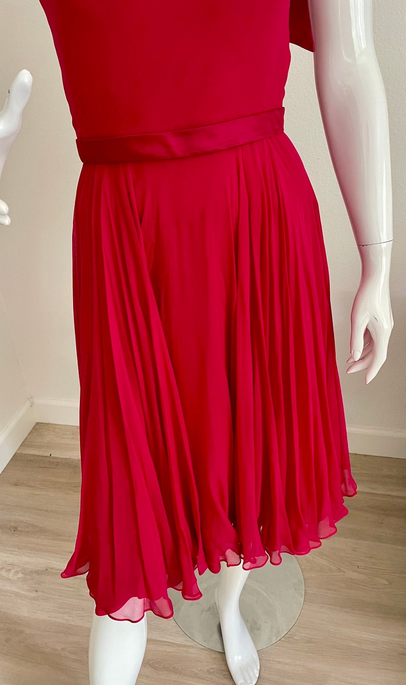 May include: A bright pink, knee-length dress with a pleated skirt and a satin waistband.