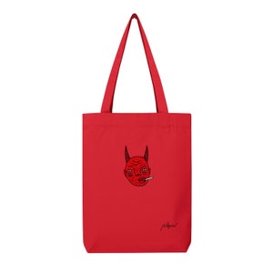 Puede incluir: Bolsa de tela roja con una ilustración en negro y rojo de un rostro de diablo con cuernos y un cigarrillo. La bolsa tiene una firma negra que dice "Playpen".