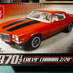 May include: A model kit box featuring a red 1970½ Chevy Camaro Z/28 with black racing stripes. The box displays the car model and the text "1970½ Chevy Camaro Z/28". The scale is 1:25.