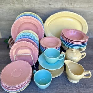May include: A set of vintage pastel-colored china teacups, saucers, and plates. The set includes a teapot, creamer, and sugar bowl. The china is decorated with a delicate scalloped edge.
