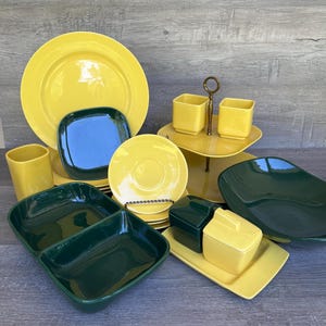 Puede incluir: Un juego de vajilla de cerámica vintage en amarillo y verde. El juego incluye un plato de cena amarillo grande, un plato amarillo más pequeño, una fuente de servir verde, una jarra de crema y un azucarero amarillos, y dos tazas amarillas.