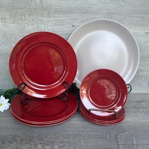 May include: Set of red and white ceramic dinner plates. The set includes a large platter, four dinner plates, and four salad plates. The plates have a glossy finish.