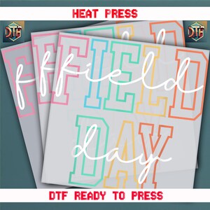 May include: A set of three heat transfer vinyl designs for a t-shirt or other apparel. The designs are in a rainbow of colors and say "Field Day" in a white cursive font.
