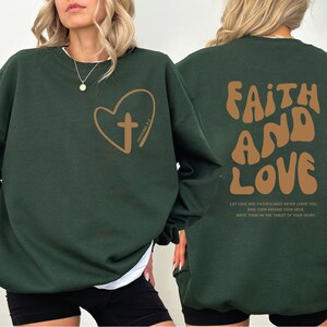 a woman wearing a green sweatshirt with a heart and a cross on it