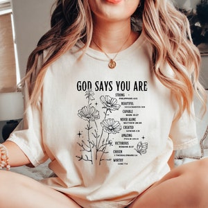 a woman sitting on a bed wearing a t - shirt that says, god says
