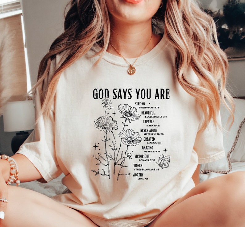 a woman sitting on a bed wearing a t - shirt that says, god says