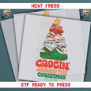 May include: A heat press transfer design featuring a Christmas tree made of colorful clogs. The design includes the text "CROCIN' AROUND THE CHRISTMAS TREE" in retro-style lettering. The words "HEAT PRESS" and "DTF READY TO PRESS" are also included.