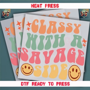 May include: A digital transfer design featuring the text "Classy with a Savage Side" in a retro, groovy font. The design includes two smiley faces and stars. The text "DTG Ready to Press" is also included.