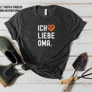May include: Dark heather grey t-shirt with white text that reads "Ich liebe Oma" and a pretzel-shaped heart.