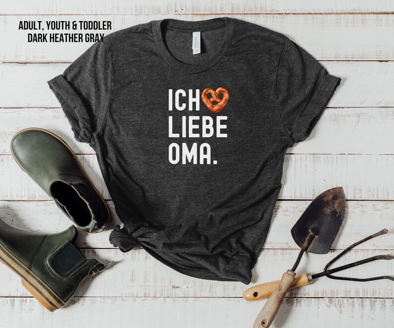 May include: Dark heather grey t-shirt with white text that reads "Ich liebe Oma" and a pretzel-shaped heart.
