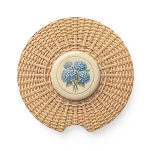 Può includere: Un sottobicchiere rotondo in ceramica con un motivo a intreccio di vimini color marrone chiaro sulla superficie. Il centro del sottobicchiere presenta un inserto circolare con sfondo crema e un'illustrazione dettagliata di ortensie blu.