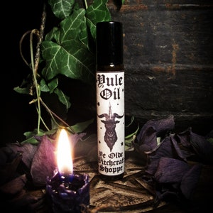 May include: A black roller bottle with a white label that reads "Yule Oil" and features a black goat with horns and a pentagram. The label also includes the text "Ye Olde Witchcraft Shoppe".
