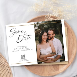 Może przedstawiać: Karta "Save the Date" z złotą ramką i czarną czcionką ozdobną. Karta zawiera zdjęcie pary uśmiechającej się do siebie. Tekst głosi "Save the Date" na ślub Katie & Paula 08.3.2025 w Charleston, SC. Dołączono kod QR z dodatkowymi informacjami.