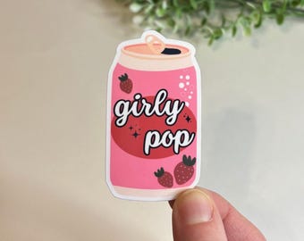 May include: Pink can with a white lid and the text "girly pop" in black. The can has a red strawberry on the front and a white background with pink bubbles.