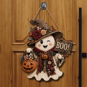Peut inclure: Une décoration murale suspendue représentant un fantôme qui fait un clin d'œil, portant un chapeau de sorcière marron orné de fleurs rouges et orange. Il tient un seau à bonbons citrouille et un panneau en bois avec l'inscription BOO!.