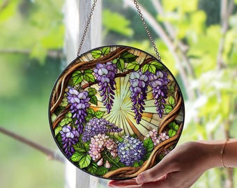 Peut inclure: Vitrail rond représentant des fleurs de glycine violettes et des feuilles vertes. Le motif floral est posé sur un fond jaune et blanc, encadré d'une bordure noire et d'une chaîne de suspension. L'œuvre mesure environ 25 cm de diamètre.