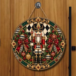 May include: A circular wooden door sign featuring a central nutcracker figure in red, black, and gold attire. The design includes a black and white diamond background, green pine branches, red bows, and gold ornaments, all framed by an ornate border.