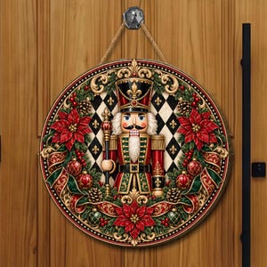 Peut inclure: Une décoration murale circulaire représentant un casse-noisette central en uniforme rouge et vert, entouré d'une couronne de poinsettias rouges, de pommes de pin et d'ornements sur un fond à motif losange noir et blanc avec des détails dorés.