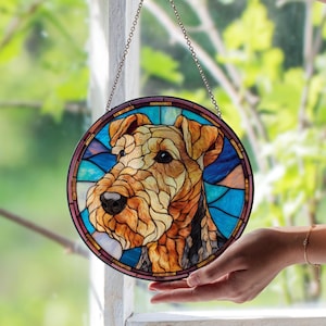May include: Round stained glass window art featuring a detailed portrait of a dog. The dog's fur is rendered in shades of brown and tan, set against a backdrop of blue and purple glass. A decorative chain is attached for hanging.