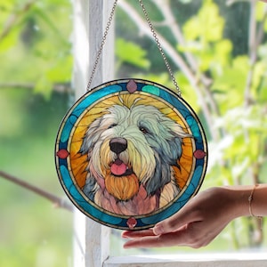May include: Round stained glass window art featuring a dog with a long, shaggy coat and a pink tongue. The dog is surrounded by a blue and yellow border with red accents. The artwork hangs from a chain.
