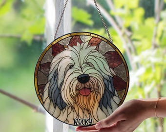 May include: A round stained glass window featuring a dog's face with the name "Rocky" at the bottom. The dog has light blue, cream, and gray fur, with a black nose and a pink tongue. The window is framed with gold and hangs from a chain.