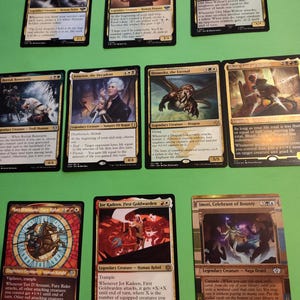 May include: A collection of ten Magic: The Gathering cards featuring various legendary creatures. The cards are arranged in two rows, with five cards in each row. The cards are all in English and feature colorful artwork.