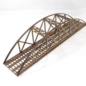 May include: A wooden model bridge with an arched design. The bridge features a lattice-style deck and intricate support structures. The wood has a natural, warm brown tone, and the bridge is set against a white background.