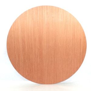 May include: A round, wooden disc with a light brown colour and a smooth, slightly textured surface. The disc has a natural wood grain pattern.