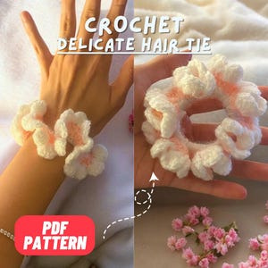 May include: A crochet hair tie with a delicate flower design in white and pink. The hair tie is shown on a hand and on a table with pink flowers. The text "CROCHET DELICATE HAIR TIE" and "PDF PATTERN" is visible in the image.