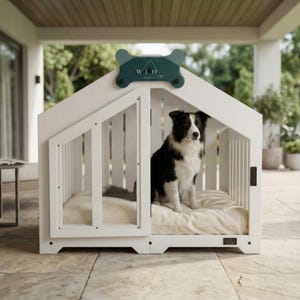 White dog house shown outdoors with a Border Collie relaxing on the cushioned interior. Ideal for indoor use or covered patios. This modern wooden dog crate provides comfort, durability, and a stylish architectural design. Perfect for small and medium breeds who enjoy fresh air and a cozy, safe resting space.