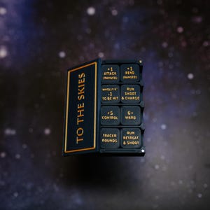 May include: A black and gold game component with the text "TO THE SKIES" and various game instructions. The component has a dark background with a starry pattern.