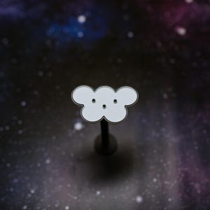 May include: A white cloud-shaped enamel pin with a black outline and two small black dots for eyes. The pin is mounted on a dark metal post, set against a starry galaxy background.