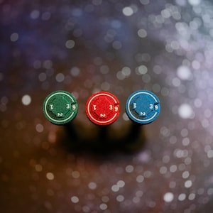 May include: Three circular markers in green, red, and blue, each featuring a textured surface with the numbers 1, 2, and 39 embossed in white. The markers are arranged horizontally, displaying a consistent design with a central circular indentation.