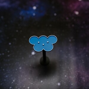 May include: A blue cloud-shaped pin with a silver outline and three small white dots. The pin is mounted on a dark gray post. The background is a dark, starry space scene.