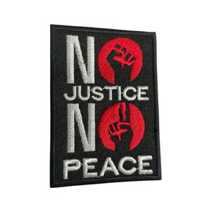 May include: Black embroidered patch with white text that reads "No Justice No Peace" and two red fists, one raised in a fist and the other in a peace sign.