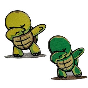 May include: Two embroidered iron-on patches of a cartoon turtle doing the dab. One turtle is green and the other is yellow.