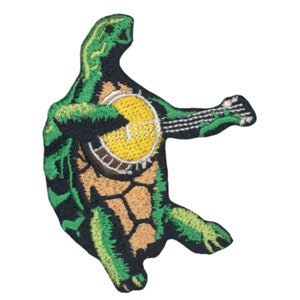 May include: Green embroidered patch of a turtle playing a banjo. The turtle is green with a brown shell and is playing a banjo with a yellow face and brown strings.