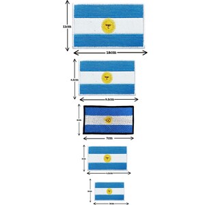 May include: Five different sizes of embroidered Argentinian flag patches. The patches are blue and white with a yellow sun in the center. The patches are 18 cm x 11 cm, 9.5 cm x 4.5 cm, 7 cm x 4 cm, 4.5 cm x 3 cm, and 3 cm x 2 cm.