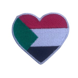 May include: A heart-shaped patch featuring the flag of Sudan. The flag is red, white, black, and green.