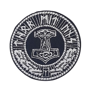 May include: A black and white embroidered patch with a circular design. The center of the patch features a silver hammer with a knot at the top. The hammer is surrounded by a circle of silver runes. The outer circle of the patch is black with a silver border.