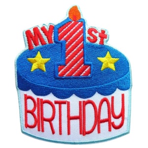 May include: An embroidered patch featuring a blue and white cake with a red and white striped candle. The cake has two yellow stars and the text "MY 1st BIRTHDAY".