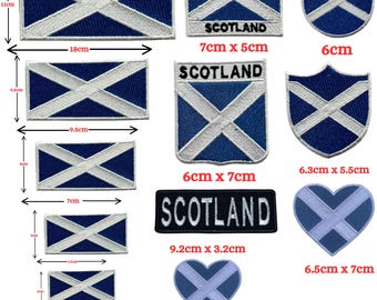 May include: A collection of embroidered patches featuring the blue and white Scottish flag in various shapes including rectangles, shields, and hearts. Some patches include the text SCOTLAND. Dimensions are provided in centimeters for each item.
