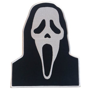 May include: Black and white embroidered patch of a ghost wearing a mask with a wide open mouth. The mask is white and the ghost is black.