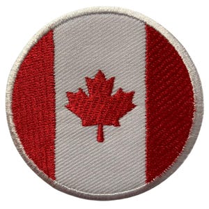 May include: A round embroidered patch featuring the Canadian flag. The flag is red and white with a red maple leaf in the center.