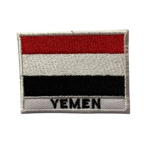May include: An embroidered patch featuring the flag of Yemen. The flag is red, white, and black with the word "YEMEN" written in black below the flag.