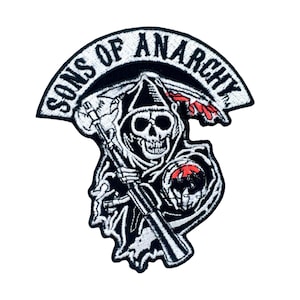 May include: Black and white embroidered patch featuring a skull wearing a hooded robe and holding a scythe. The patch has the text "Sons of Anarchy" in a white arch above the skull.