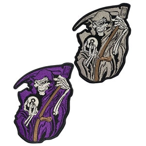 May include: Two embroidered patches featuring the Grim Reaper. One patch is purple with a white skull and bone hands, holding a small orb. The other patch is gray with a similar design. Both patches have a black border.