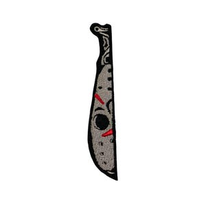 Könnte beinhalten: Schwarzer und weißer gestickter Aufnäher einer Machete mit einer weißen und grauen Hockeymaske auf der Klinge. Die Maske hat rote Akzente.