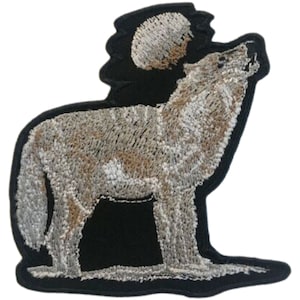 May include: Embroidered patch of a grey wolf howling at the moon. The wolf is standing on a white snowy ground. The moon is full and white.